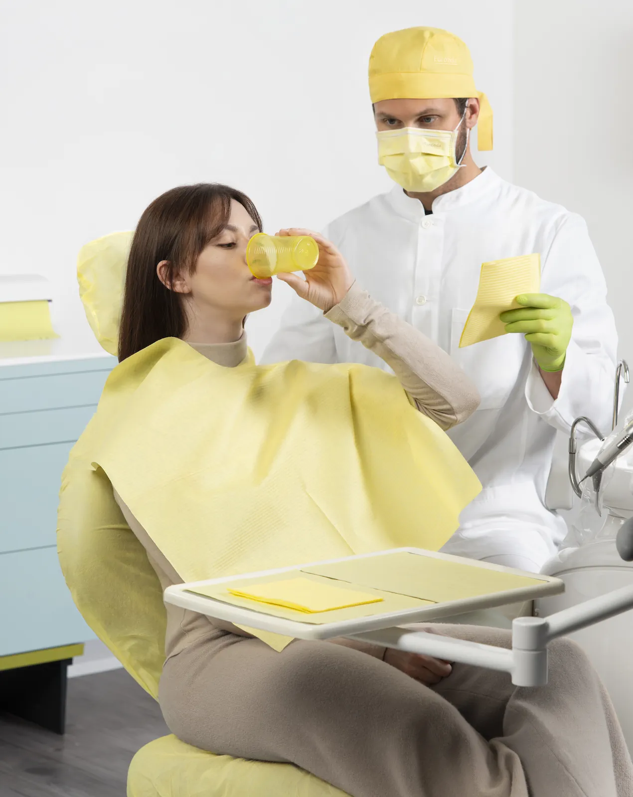 Patientin mit gelbem Bib UP! Umhang auf einem Zahnarztstuhl